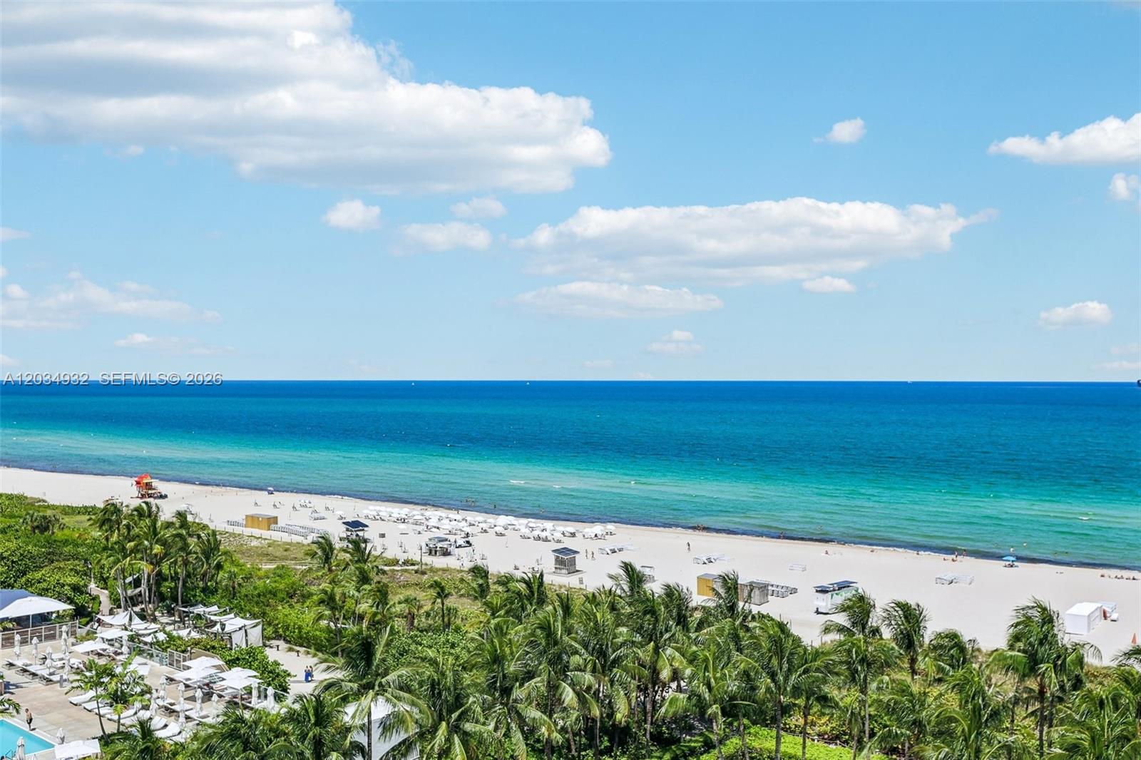 An elevated view shows a sandy beach with palm trees and the ocean beyond — 2201 Collins Ave # 1019, Miami Beach FL 33139, MIAMI BEACH, FL