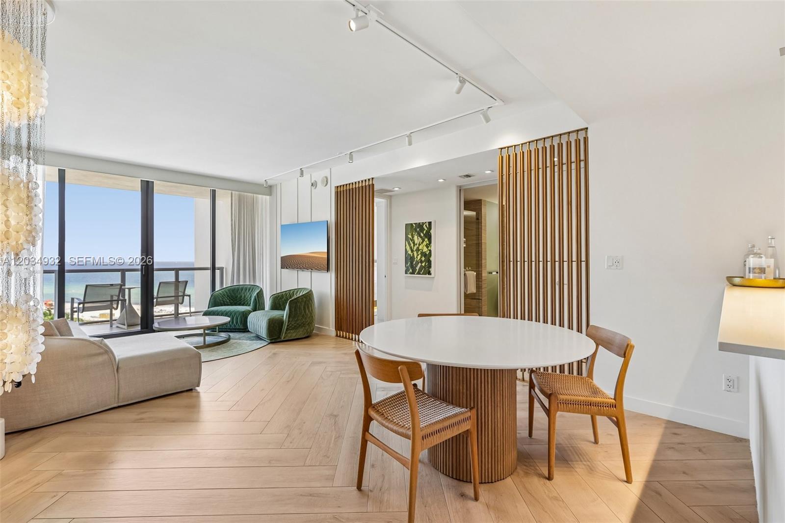 A modern living and dining area features light wood floors, a round table, and ocean views — 2201 Collins Ave # 1019, Miami Beach FL 33139, MIAMI BEACH, FL