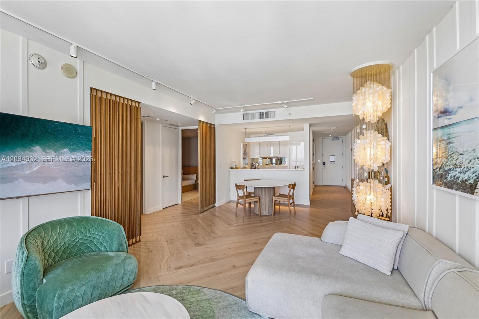 A living room features a green armchair, a light sofa, and a dining area — 2201 Collins Ave # 1019, Miami Beach FL 33139, MIAMI BEACH, FL
