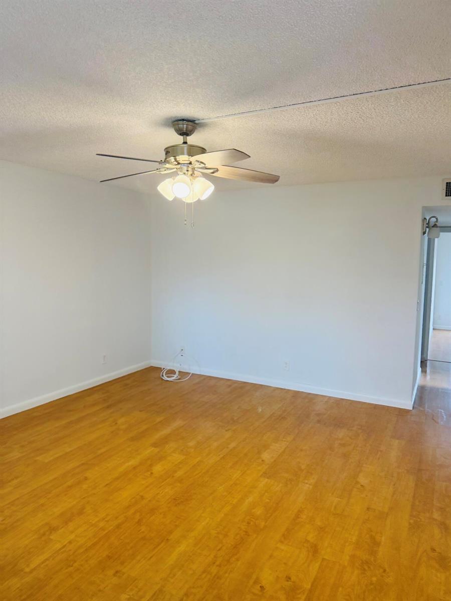 An empty room with light wood-look flooring, white walls, and a ceiling fan with lights — 490 Normandy # K, Delray Beach FL 33484, DELRAY BEACH, FL