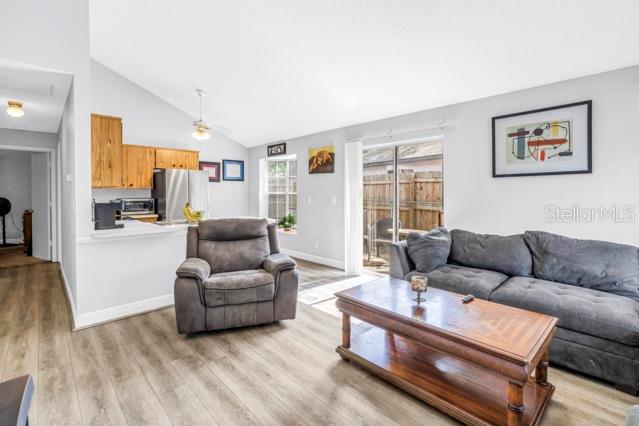 A living room with wood-look flooring, a gray sofa, a recliner, and an open kitchen — 2672 MEGAN COURT, PALM HARBOR, FL
