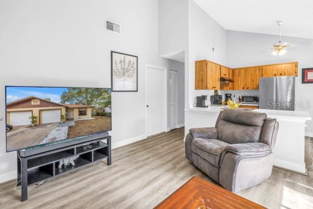 A living room features a television on a stand, a recliner, and an open kitchen — 2672 MEGAN COURT, PALM HARBOR, FL