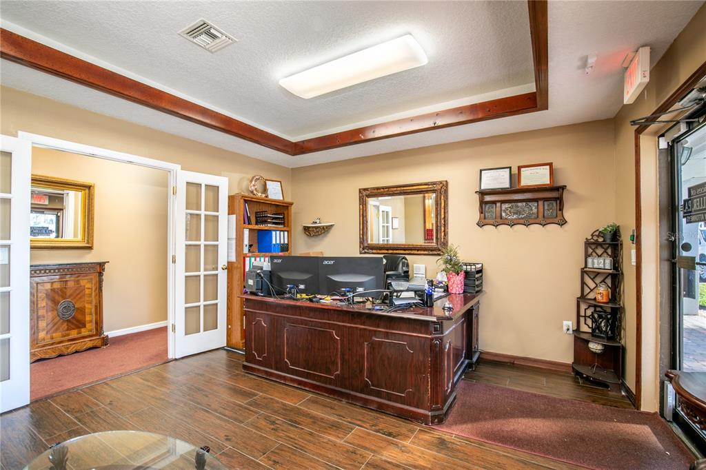 An office space features a dark wood desk, wood-look flooring, and a framed mirror — 205 E BURLEIGH BOULEVARD, TAVARES, FL