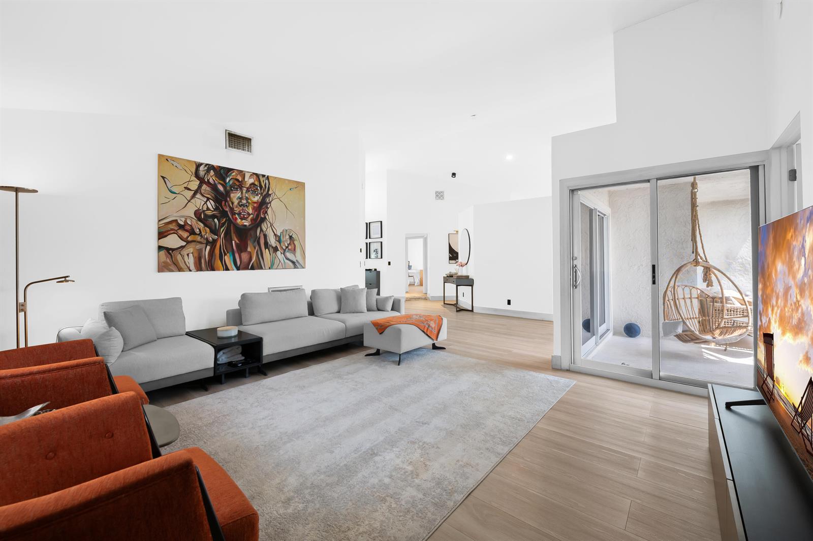 A living room features a grey sectional, orange armchairs, a large painting, and a patio — 22448 Swordfish Drive, Boca Raton FL 33428, BOCA RATON, FL