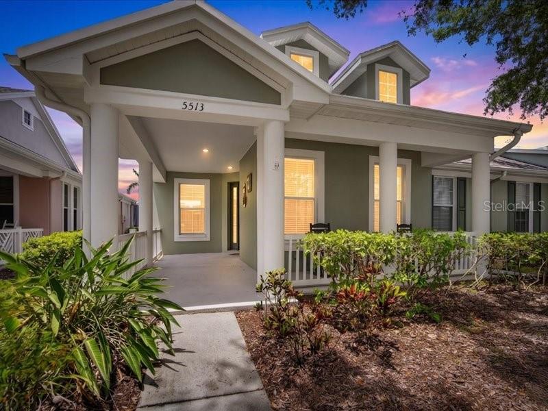 A green house with a covered front porch, white columns, and a concrete walkway — 5513 GOLDEN ISLES DRIVE, APOLLO BEACH, FL