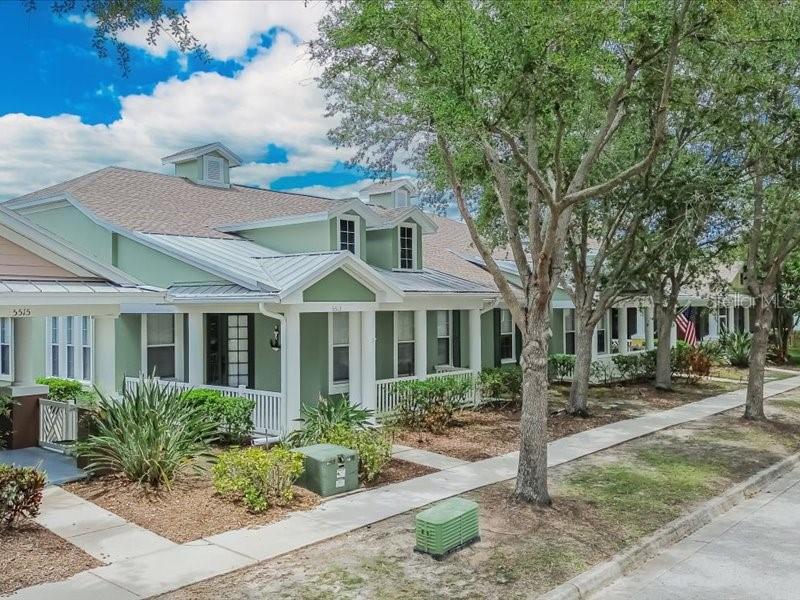 A light green house with a metal roof and front porch sits along a sidewalk — 5513 GOLDEN ISLES DRIVE, APOLLO BEACH, FL