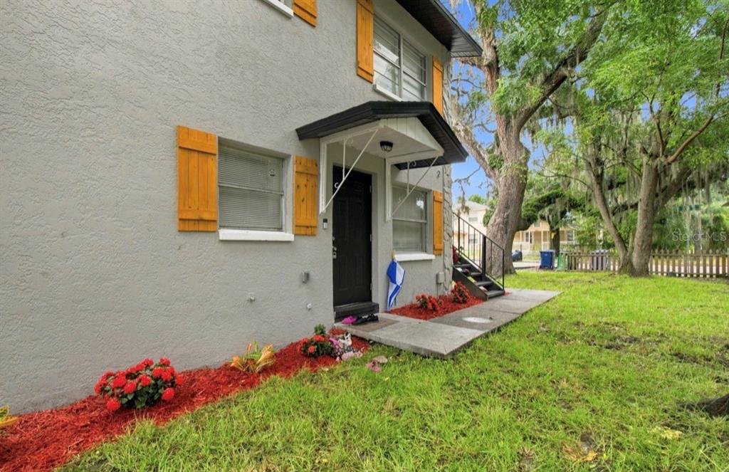 A two-story gray building with wood shutters, a small front porch, and red mulch landscaping — 8602 N 14TH STREET, TAMPA, FL