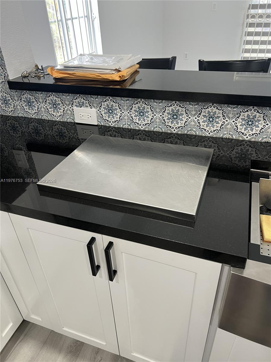 A kitchen counter features a stainless steel cover over the stove and patterned backsplash tiles — 9000 W Flagler St # 1, Miami FL 33174, MIAMI, FL