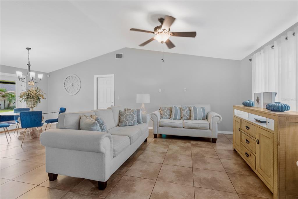 A living room with light gray walls, tile flooring, a ceiling fan, and neutral furniture — 819 JACARANDA DRIVE, OLDSMAR, FL