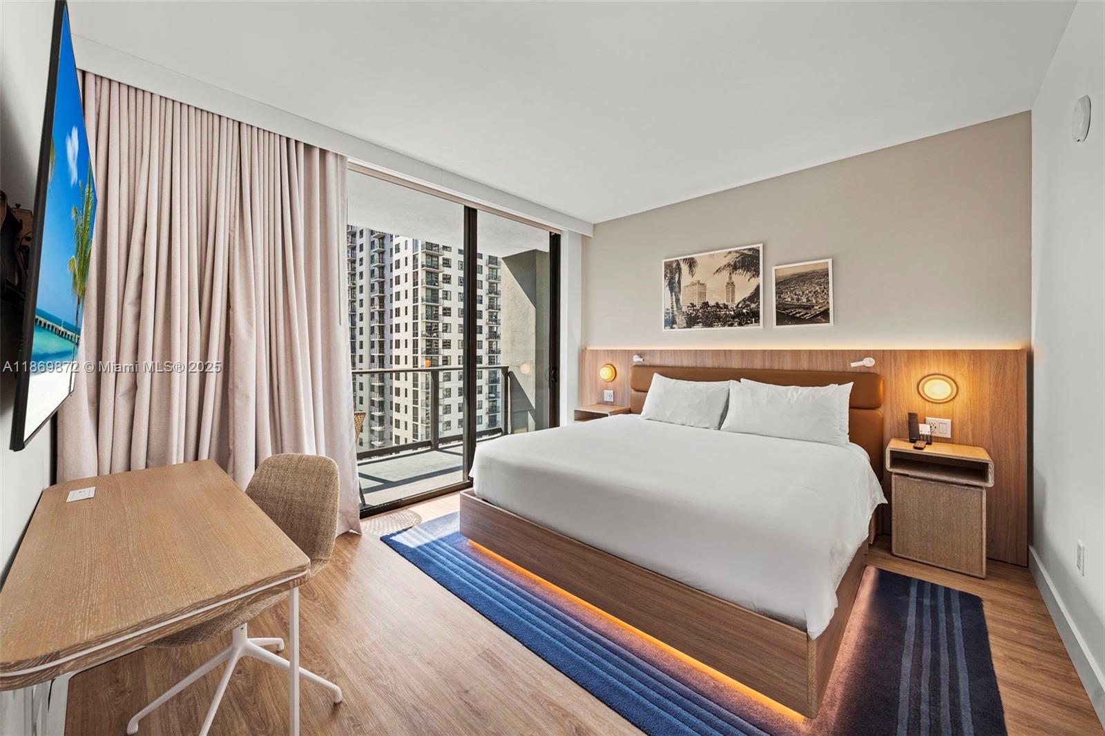 A modern hotel bedroom features a king bed, wood-toned furniture, and a balcony with city views — 601 NE 1st Ave # 1803, Miami FL 33132, MIAMI, FL