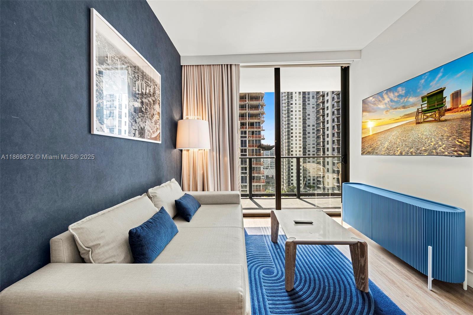 A living room features a blue accent wall, a beige sofa, and a blue media console — 601 NE 1st Ave # 1803, Miami FL 33132, MIAMI, FL
