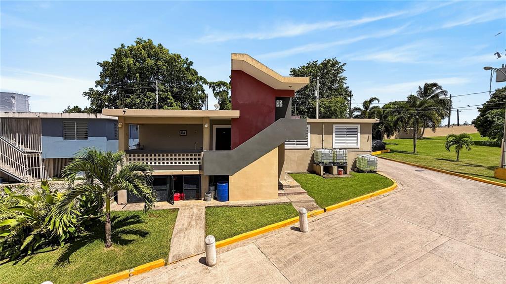 A two-story building with a red accent wall, exterior staircase, and a paved driveway — 120 BO HATO TEJAS, CALLE PAJAROS, BAYAMON, PR