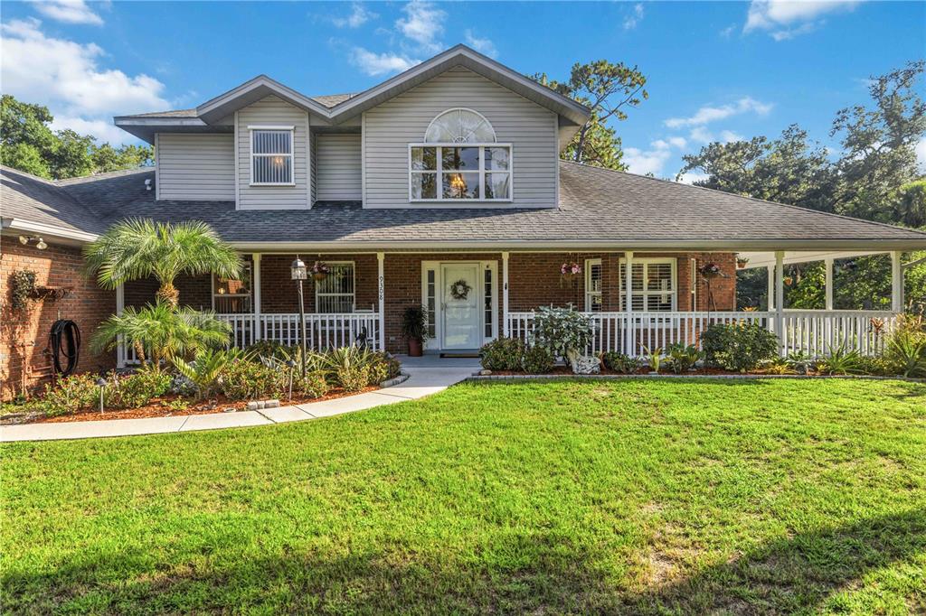 A two-story house with a brick and gray siding exterior features a front porch — 9308 65TH AVENUE E, BRADENTON, FL