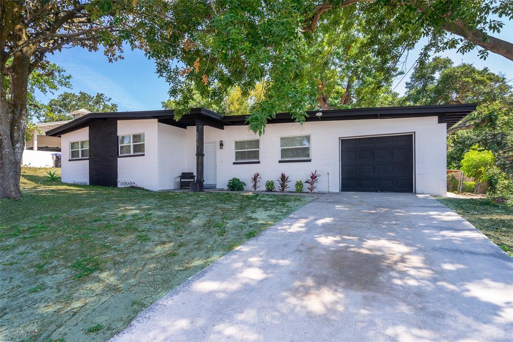 A single-story house with white painted brick, black trim, and a one-car garage — 5815 WOLF ROAD, ORLANDO, FL