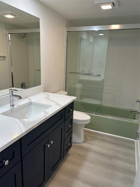 An empty room features light-colored wood-look flooring, white walls, a ceiling fan, and large windows — 4520 OVERLOOK DRIVE NE UNIT 132, ST PETERSBURG, FL