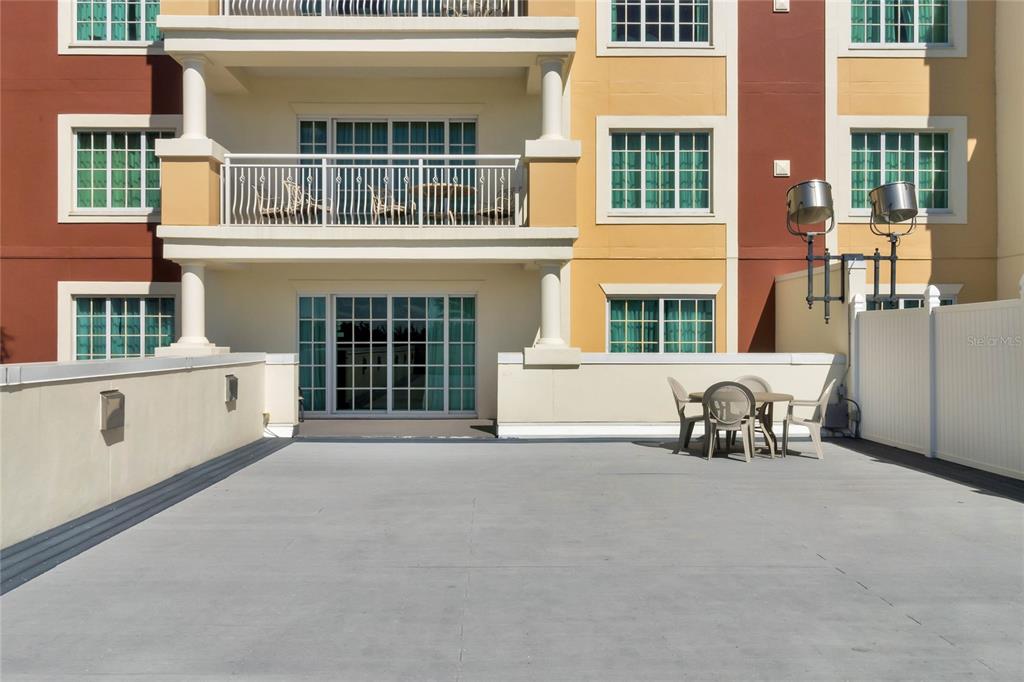 A large, flat outdoor terrace features a small dining set and a white privacy fence — 7593 GATHERING DRIVE UNIT 206, REUNION, FL