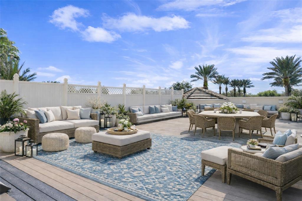 A spacious outdoor deck features wicker furniture, a large blue rug, and a white fence — 7593 GATHERING DRIVE UNIT 206, REUNION, FL