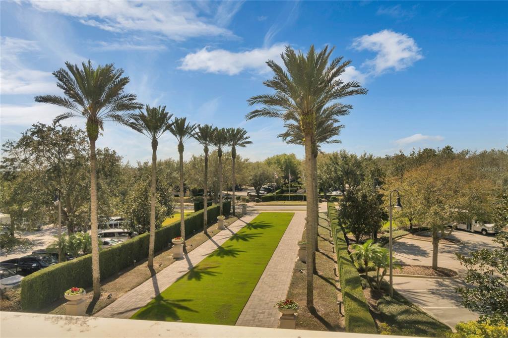 An elevated view shows a landscaped walkway lined with palm trees between two parking lots — 7593 GATHERING DRIVE UNIT 206, REUNION, FL