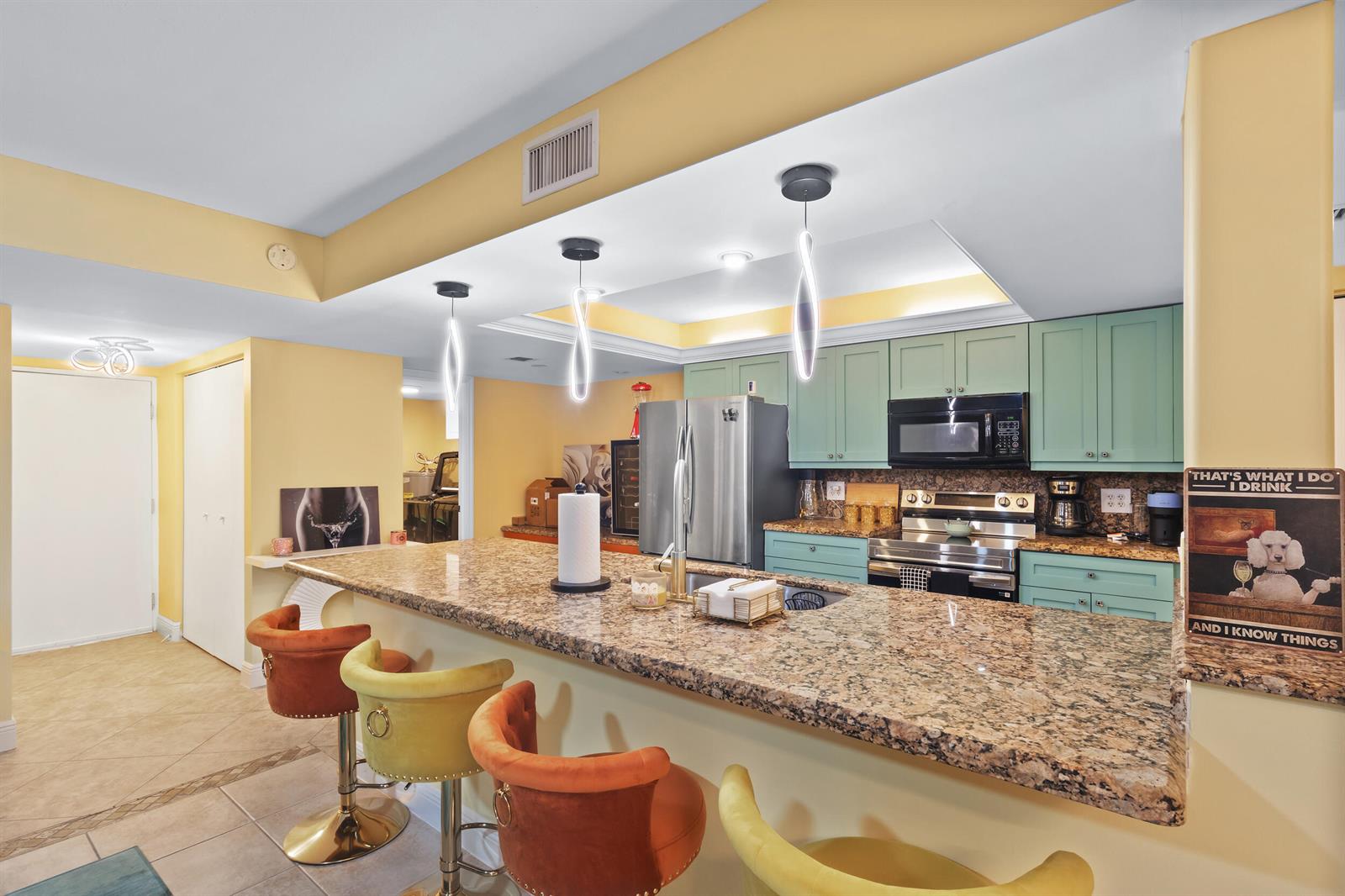A kitchen features light green cabinets, granite countertops, a breakfast bar, and four colorful stools — 500 Egret Circle # 8208, Delray Beach FL 33444, DELRAY BEACH, FL