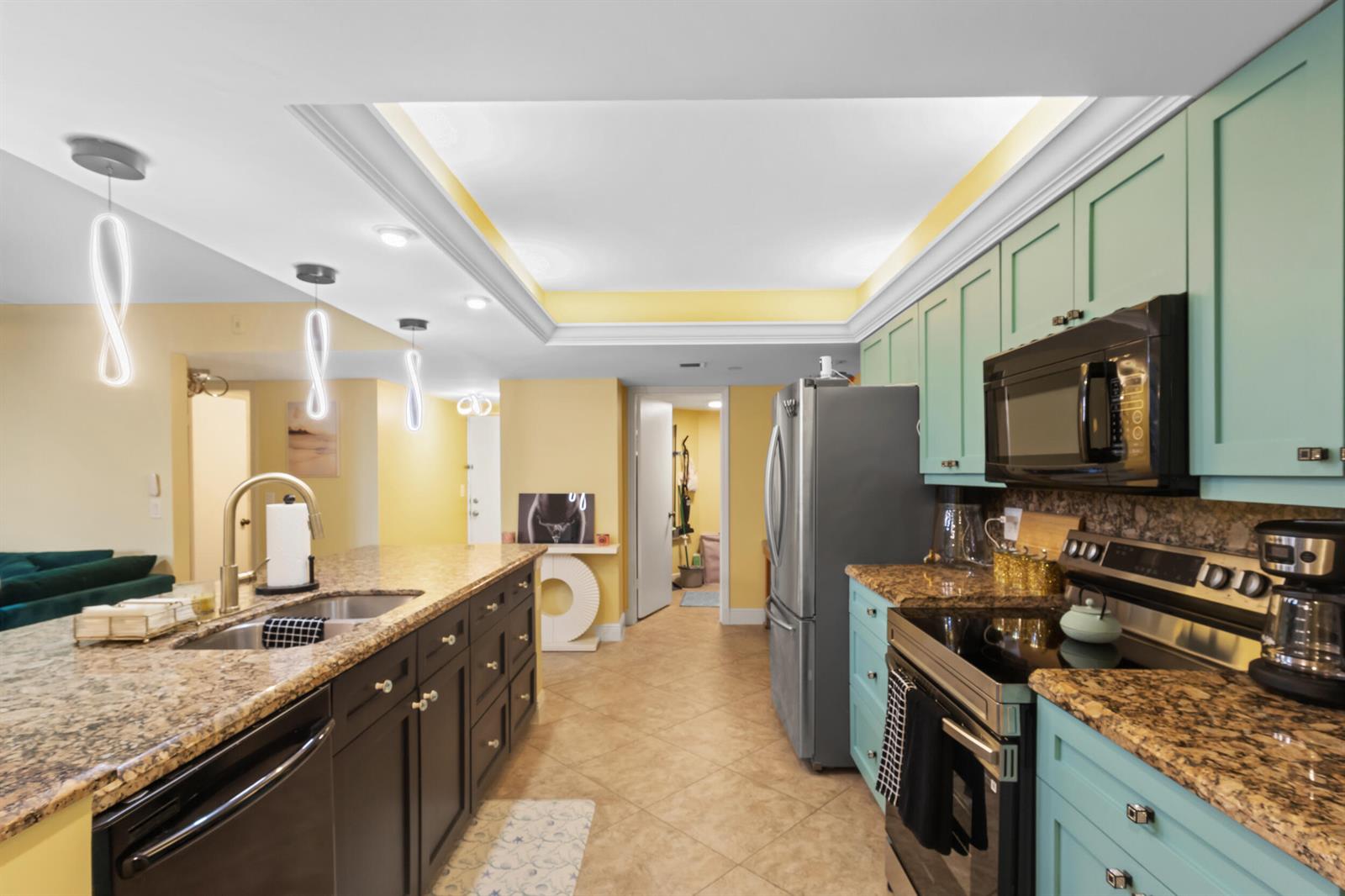 A kitchen features teal and dark brown cabinetry, granite countertops, and a large island — 500 Egret Circle # 8208, Delray Beach FL 33444, DELRAY BEACH, FL