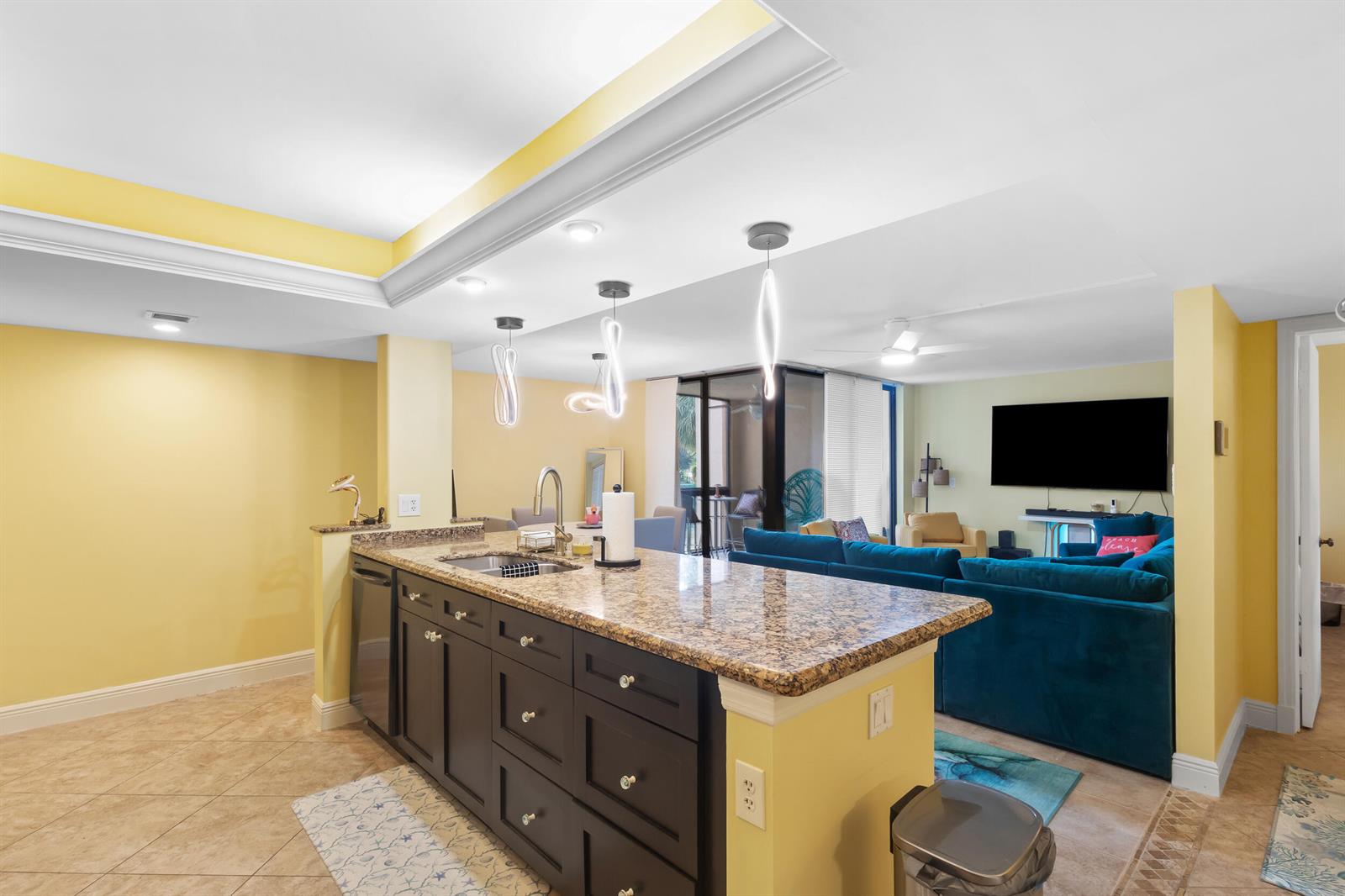 A kitchen island with dark cabinets and granite countertops overlooks a living room with furniture — 500 Egret Circle # 8208, Delray Beach FL 33444, DELRAY BEACH, FL