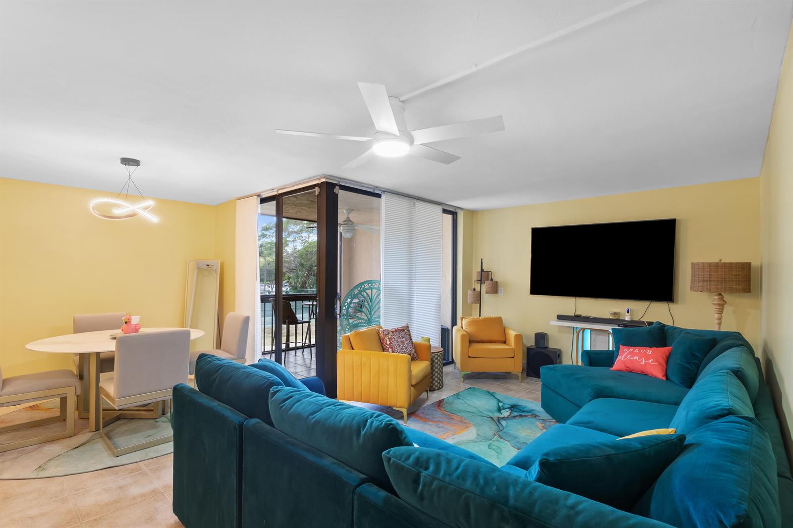 A living and dining area features yellow walls, a teal sectional, and a glass balcony door — 500 Egret Circle # 8208, Delray Beach FL 33444, DELRAY BEACH, FL
