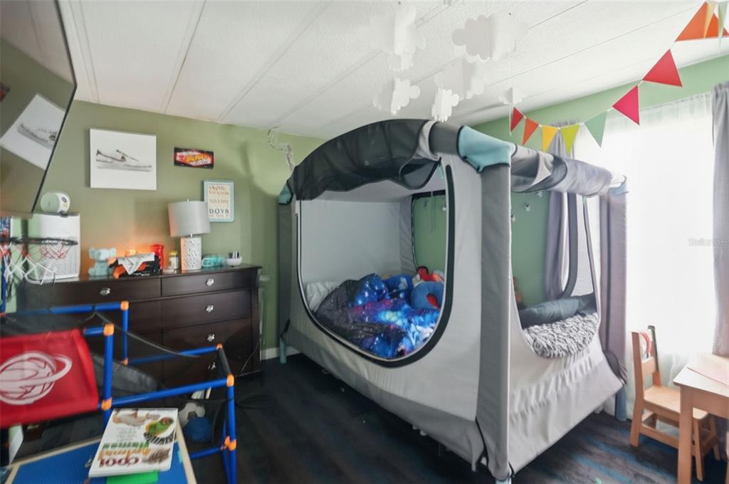 A child's bedroom features a large enclosed bed tent, a wooden dresser, and colorful wall decor — 8604 CAMEO DRIVE, NEW PORT RICHEY, FL