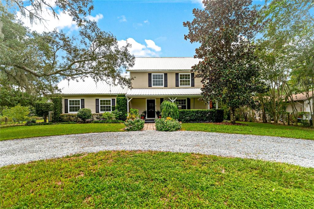 A two-story house with a metal roof and a gravel driveway sits on a lawn — 29249 WILPAYNE ROAD, BROOKSVILLE, FL