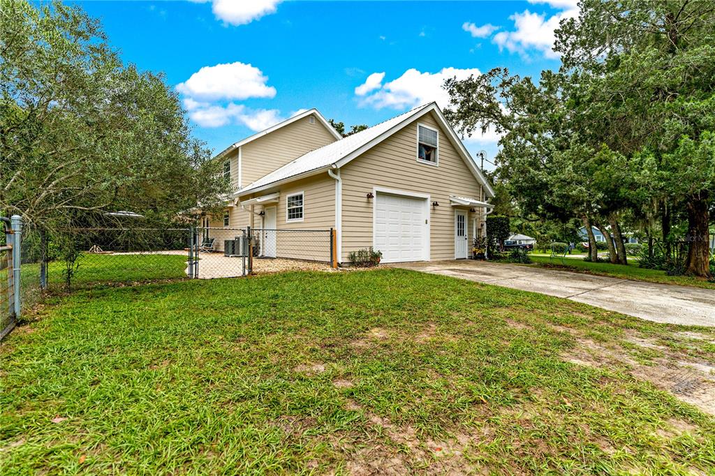 A beige two-story house with a white garage door and a chain-link fenced yard — 29249 WILPAYNE ROAD, BROOKSVILLE, FL
