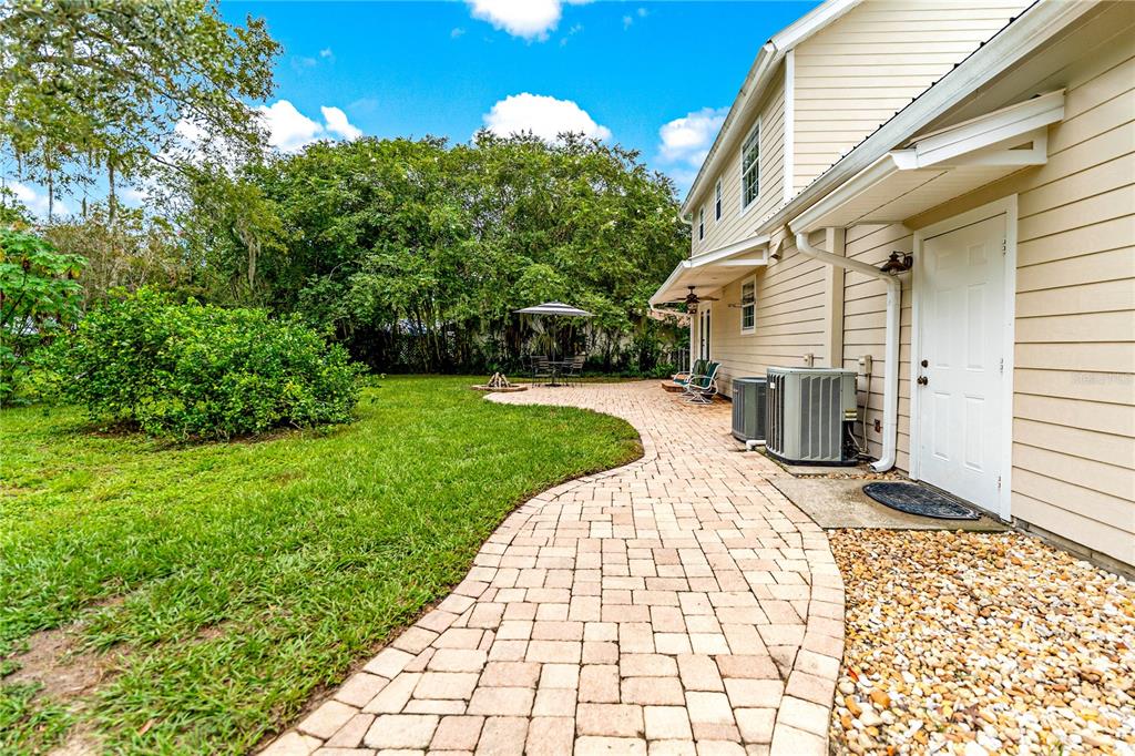 A paved walkway leads along the side of a house toward a backyard patio area — 29249 WILPAYNE ROAD, BROOKSVILLE, FL