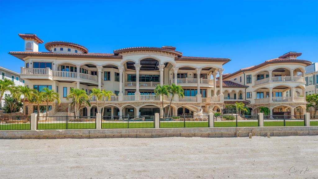 A large, multi-story Mediterranean-style mansion with balconies and columns sits behind a black metal fence — 1700 GULF BOULEVARD, BELLEAIR BEACH, FL