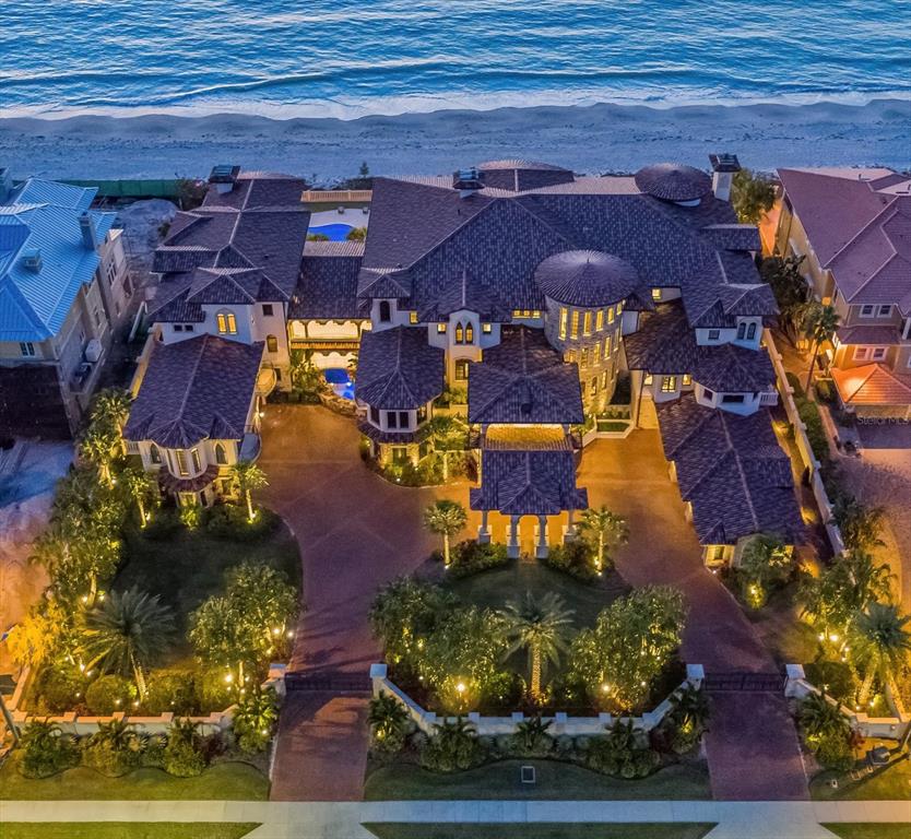 An aerial view of a large, multi-roofed luxury beachfront mansion with a paved circular driveway — 1700 GULF BOULEVARD, BELLEAIR BEACH, FL