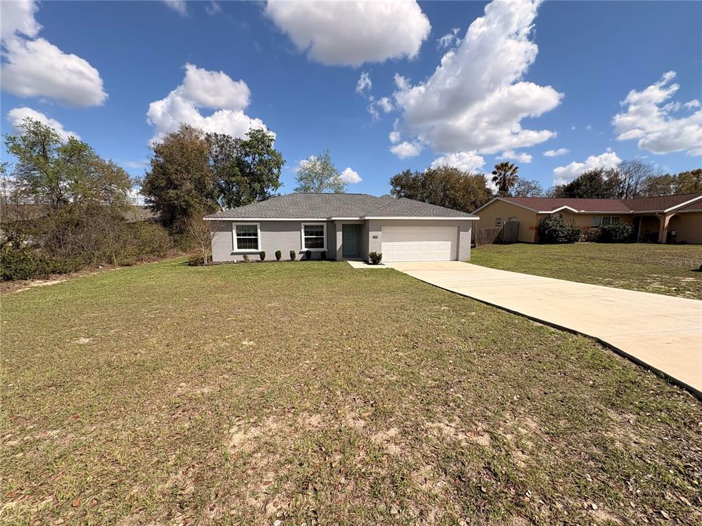 A single-story house with a gray exterior, a two-car garage, and a large front lawn — 15705 SW 19TH AVENUE ROAD, OCALA, FL