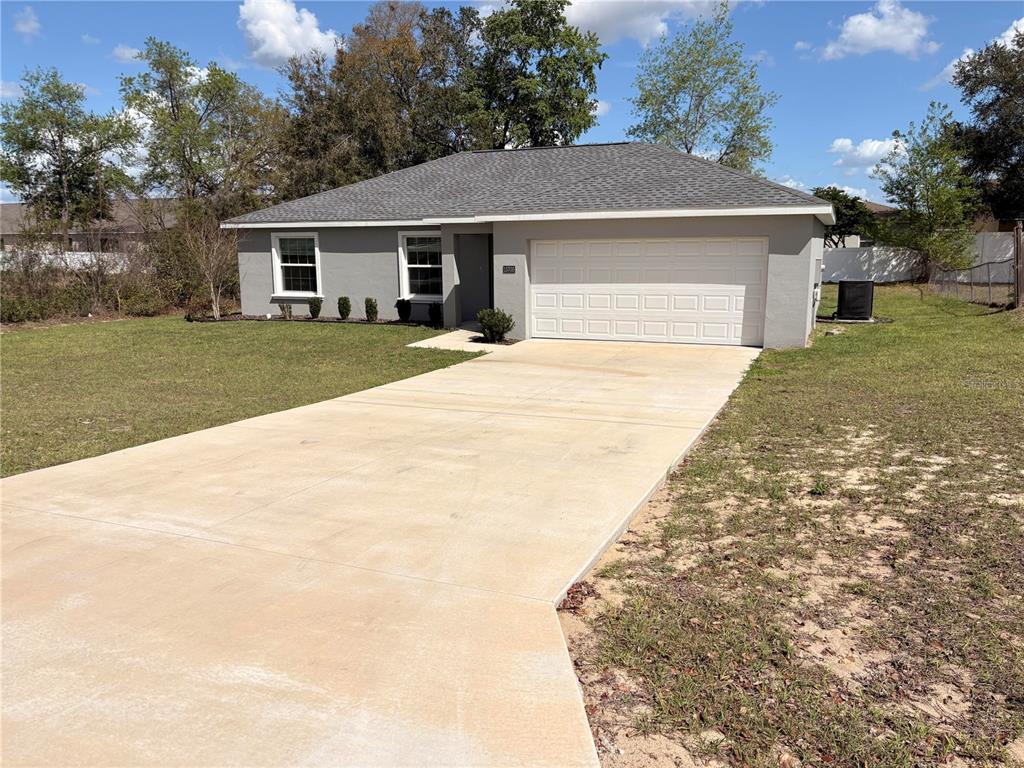 A single-story gray house with a white garage door and a concrete driveway — 15705 SW 19TH AVENUE ROAD, OCALA, FL