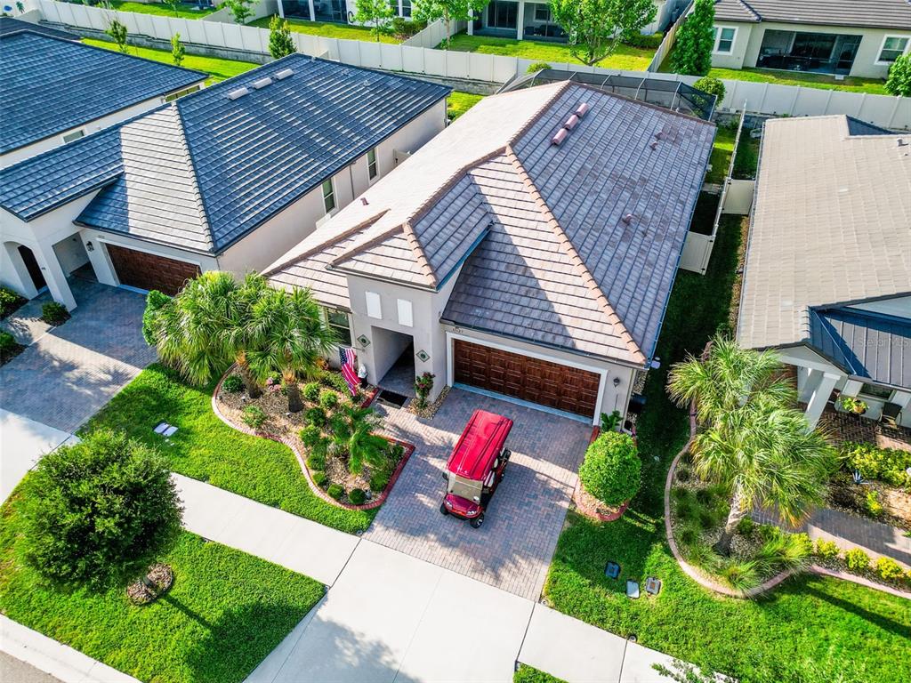 An aerial view shows a single-story house with a tiled roof, garage, and golf cart — 31527 CANNON RUSH DRIVE, SAN ANTONIO, FL