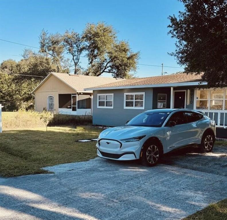 A light blue electric SUV is parked in the driveway in front of a house — 4910 HUPPEL AVENUE, ORLANDO, FL