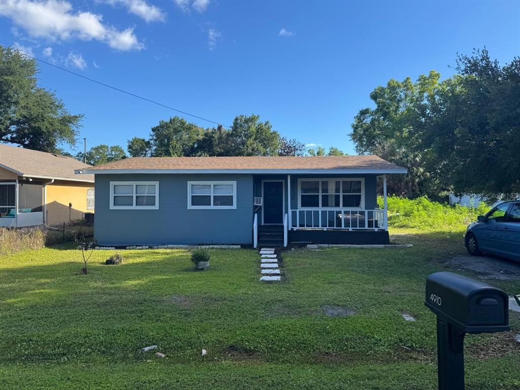 A single-story blue house with a front porch and a grassy yard under a blue sky — 4910 HUPPEL AVENUE, ORLANDO, FL