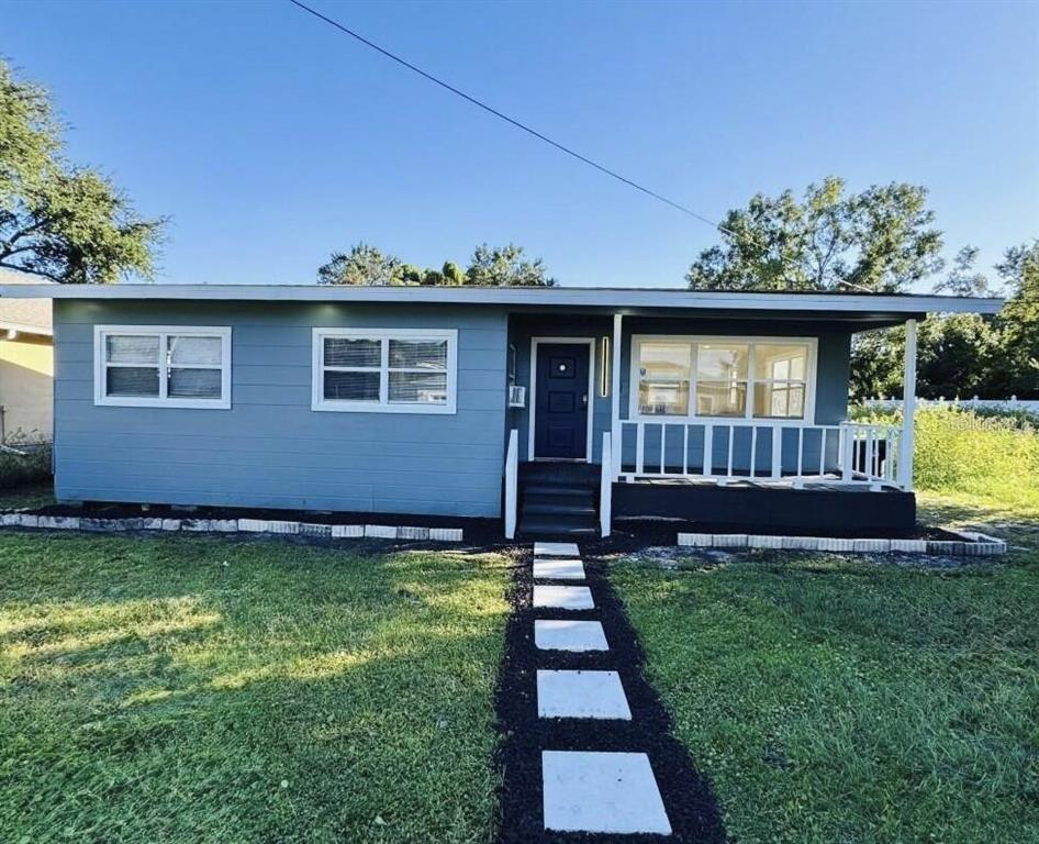 A single-story blue house features a front porch, white trim, and a stone walkway — 4910 HUPPEL AVENUE, ORLANDO, FL