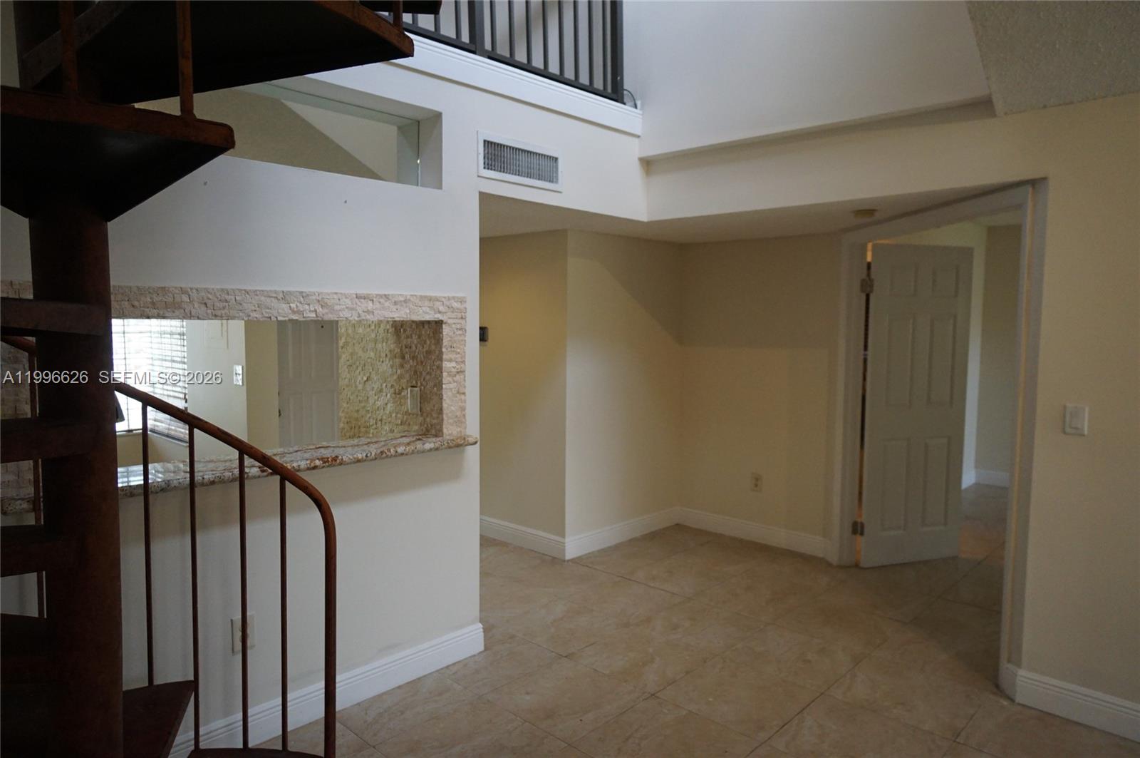 A spiral staircase stands next to a tiled room with a stone-accented pass-through window — 13015 SW 88th Ter S # B, Miami FL 33186, MIAMI, FL