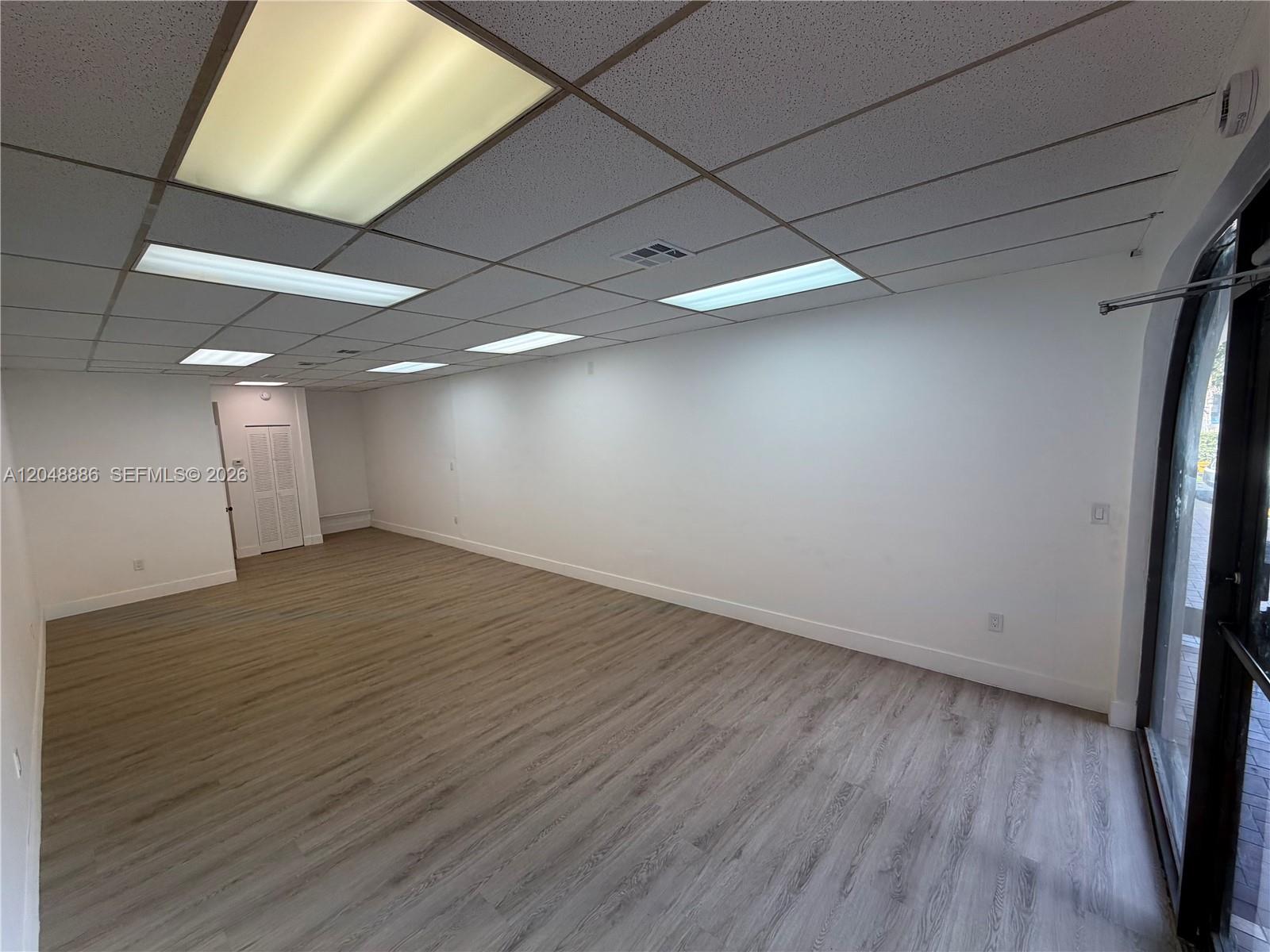 An empty commercial space features white walls, wood-look flooring, and a drop ceiling with lights — 503 SW 12th Ave, Miami FL 33130, MIAMI, FL