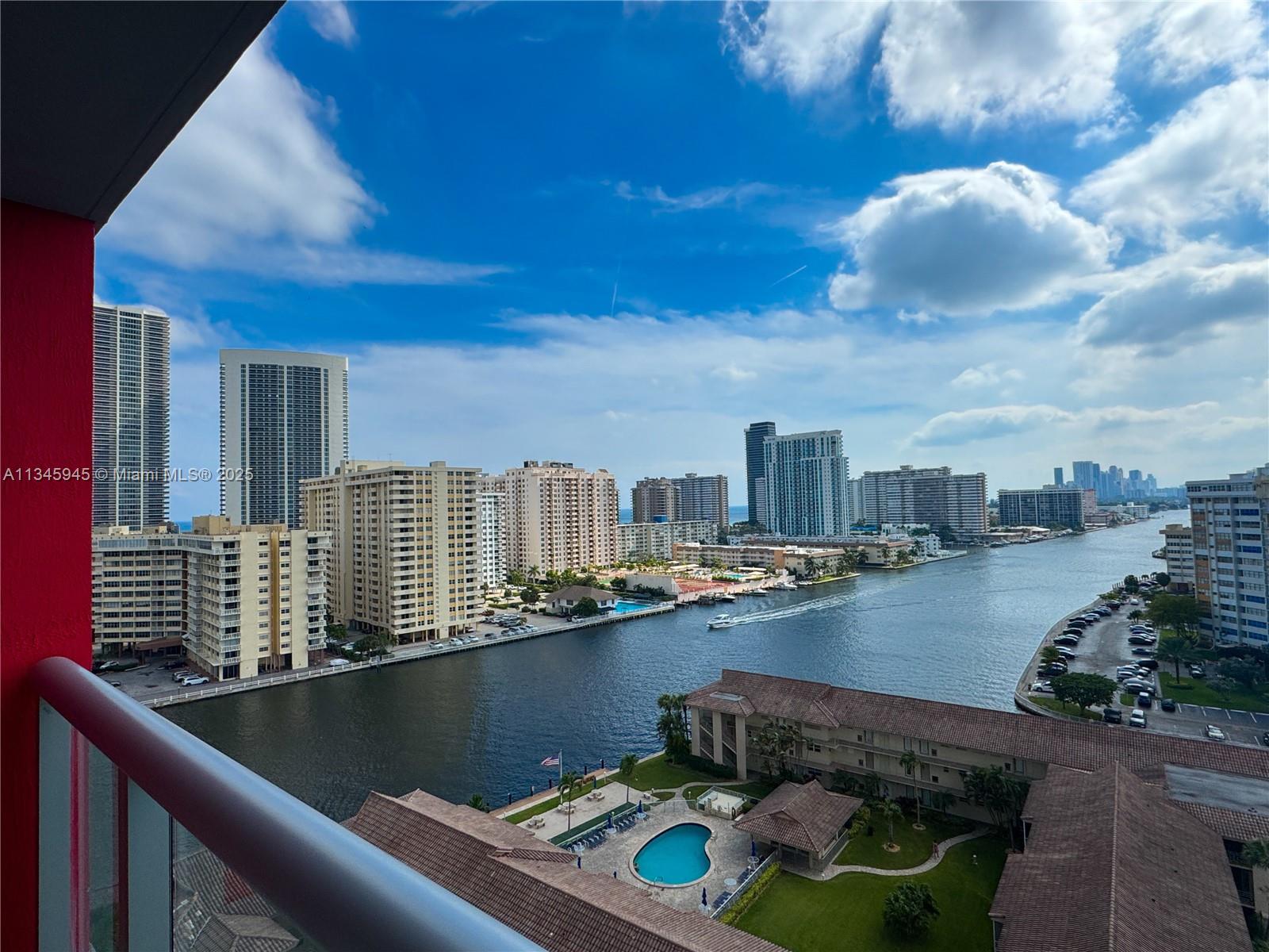 A high-angle view from a balcony overlooks a waterway, surrounding apartment buildings, and a pool — 2602 E HALLANDALE BEACH BLVD # R1409, Hallandale Beach FL 33009, HALLANDALE BEACH, FL