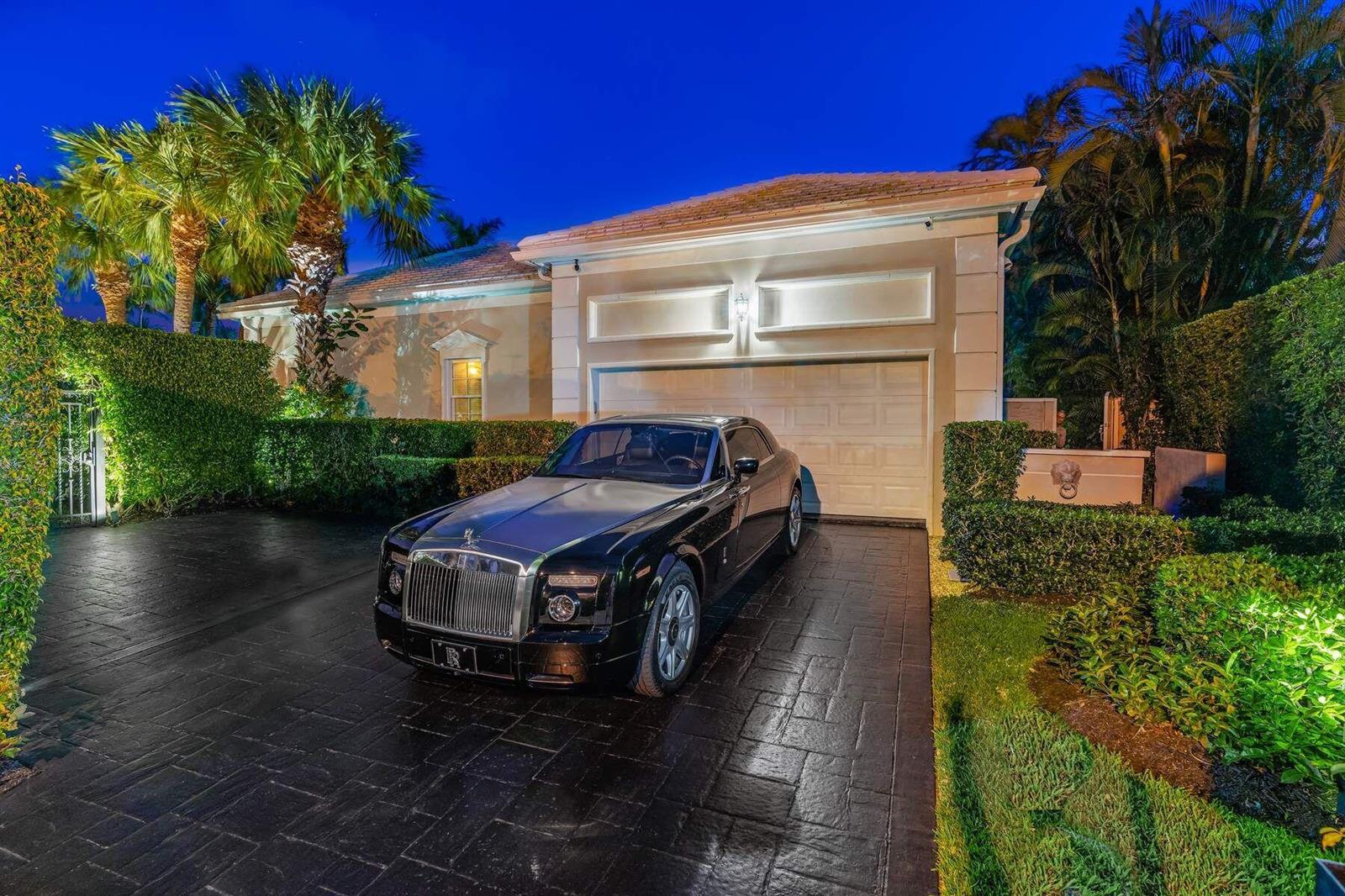 A black Rolls-Royce is parked on a paved driveway in front of a house at night — 710 N COUNTY Road, Palm Beach FL 33480, PALM BEACH, FL