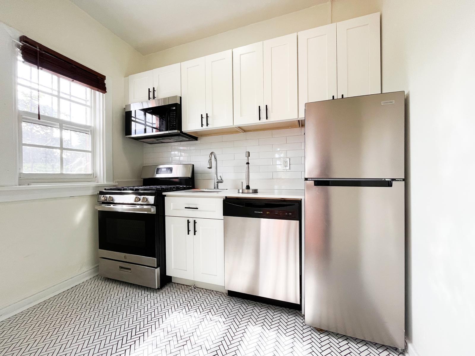 A kitchen features white cabinets, stainless steel appliances, a subway tile backsplash, and herringbone flooring — 623 Park Place # 6, West Palm Beach FL 33401, WEST PALM BEACH, FL