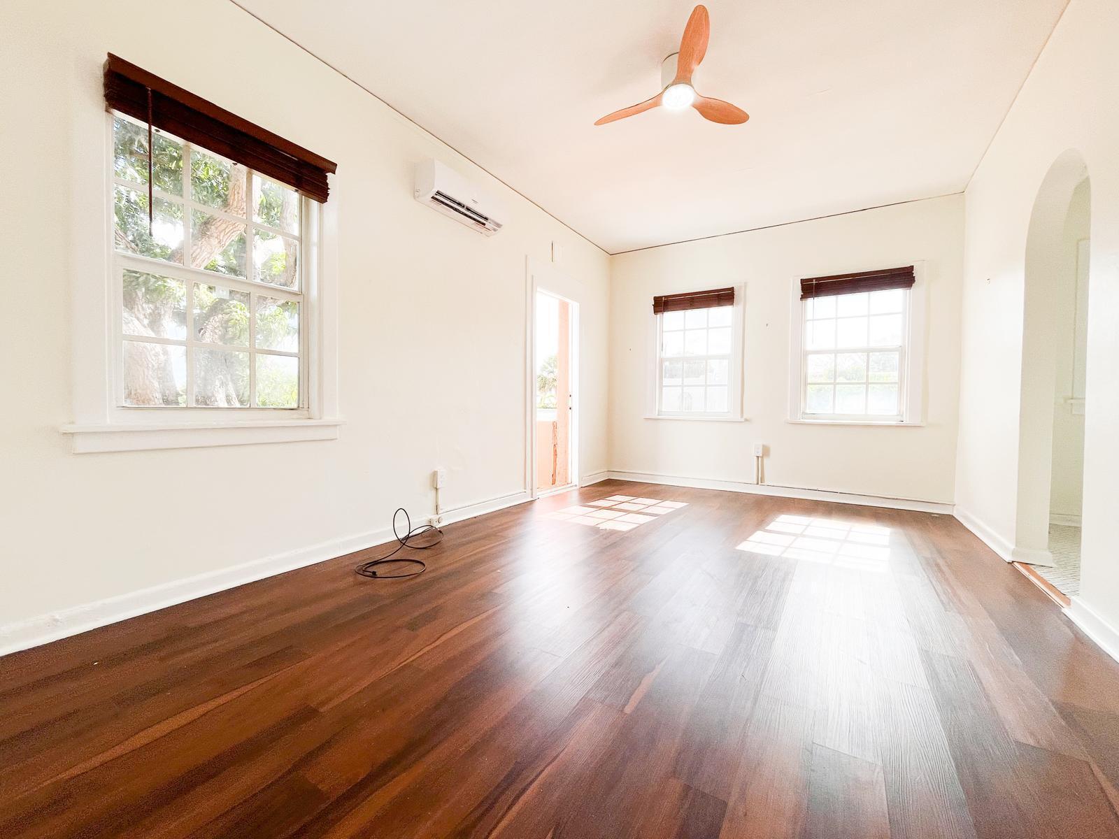 An empty room with dark wood flooring, white walls, three windows, and a ceiling fan — 623 Park Place # 6, West Palm Beach FL 33401, WEST PALM BEACH, FL
