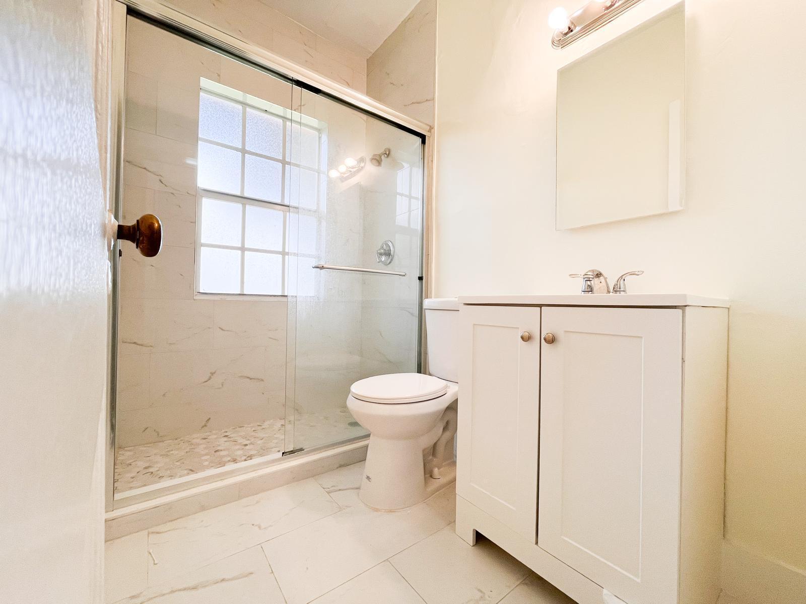 A bathroom features a glass-enclosed walk-in shower, a white vanity, and a toilet — 623 Park Place # 6, West Palm Beach FL 33401, WEST PALM BEACH, FL
