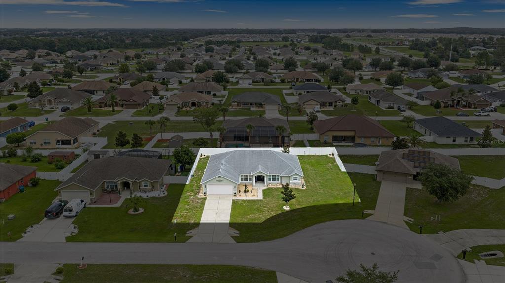 An aerial view shows a single-story house with a white fence and a concrete driveway — 9957 SW 55TH AVENUE ROAD, OCALA, FL