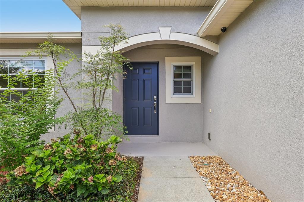 A blue front door is set under an arched entryway next to a small window — 340 BELLA ROSA CIRCLE, SANFORD, FL