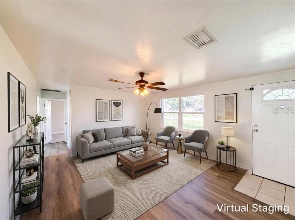 A living room with wood-look flooring, a gray sofa, two armchairs, and a coffee table — 2710 WOODLAWN DRIVE, WINTER HAVEN, FL