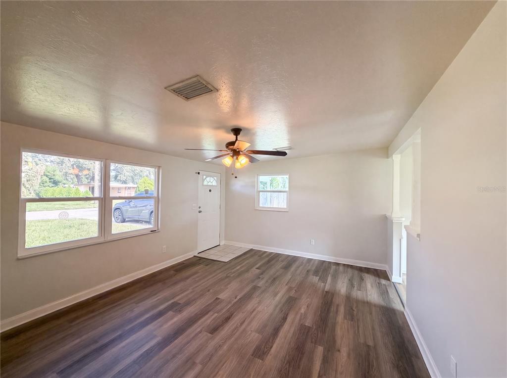 An empty living room with wood-look flooring, a ceiling fan, and a front entry door — 2710 WOODLAWN DRIVE, WINTER HAVEN, FL