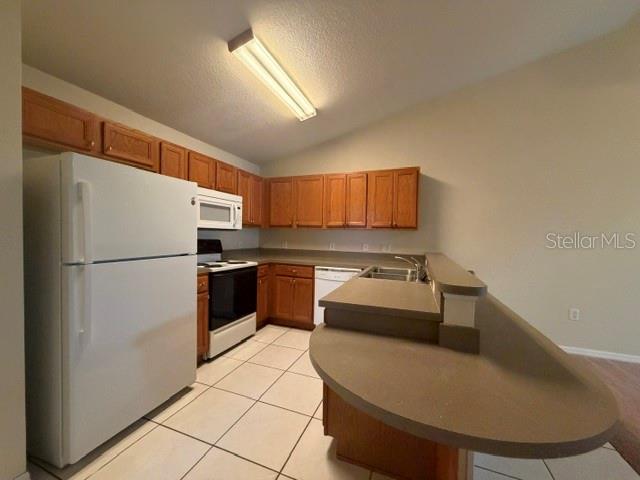 A kitchen features wood cabinets, a white refrigerator, and a curved breakfast bar — 31-33 E ST LOUIS AVENUE, EUSTIS, FL